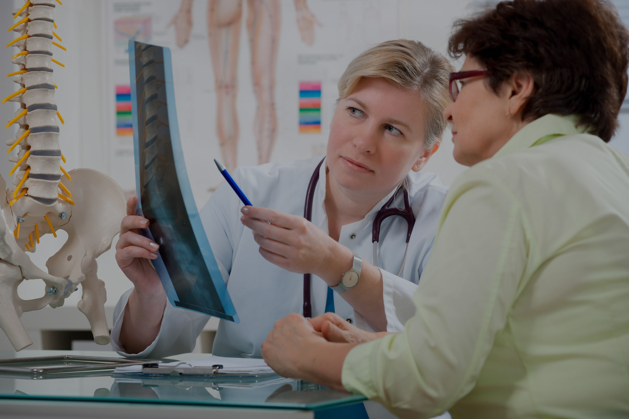 A doctor shows a patient a x-ray of the human spine.