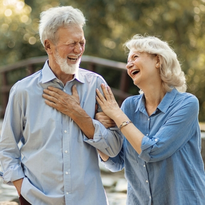 Older couple walking outdoors and laughing together.