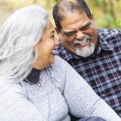 Older couple laughing together outdoors.